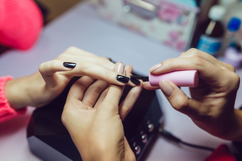 técnico manicurista pintando uñas de negro